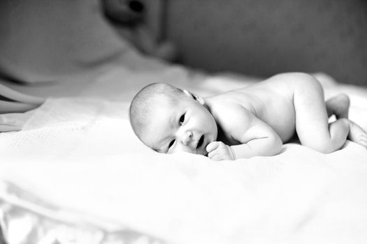 black-and-white photo in retro style.portrait of a newborn baby in the parents ' bed.the photo has a empty space for your text