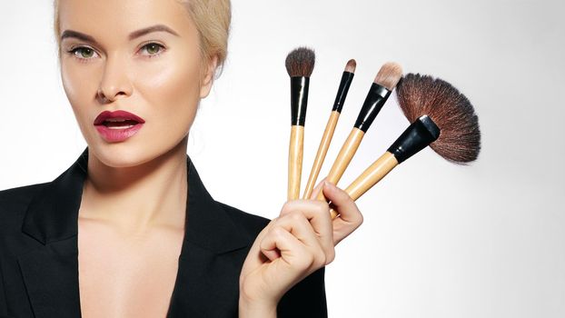 Beauty Treatment. Girl with Makeup Brushes. Fashion Make-up for Sexy Woman. Makeover. Make-up Artist Applying Visage on white background