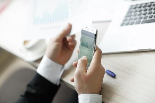 closeup.businessman checks the financial data using a smartphone.the business concept
