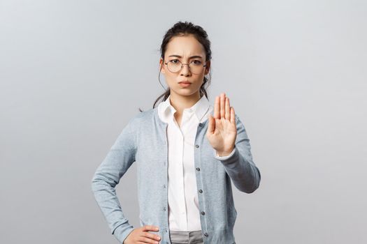 People, emotions and lifestyle concept. Tell you to stop. Serious-looking young strict asian female tutor, teacher or employee raising hand in rejection, disapprove and warning, prohibit action.