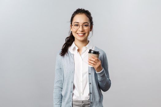 Lifestyle, people and emotions concept. Attractive young woman, female employee buying take-away coffee on her way to work office, smiling cheerful, casual ordinary day with coworkers doing their job.