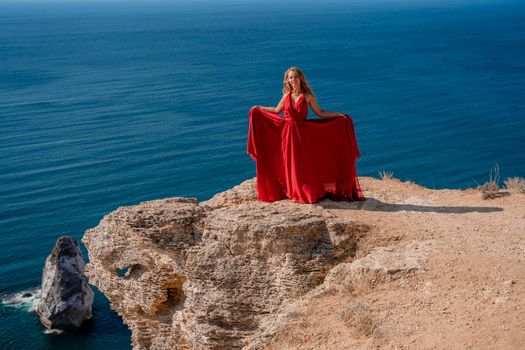 A woman in a red flying dress fluttering in the wind, against the backdrop of the sea