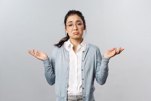 Well, we have nothing to do about it, cant deal problem. Portrait of indecisive or desperate asian woman shrugging and raise hands sideways perplexed, dont know cant tell, being clueless.