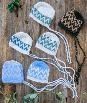 set of tender knitted hats for newborn on wooden background
