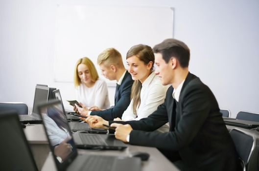 business, technology and office concept - smiling business team with laptop computers and documents having discussion in office