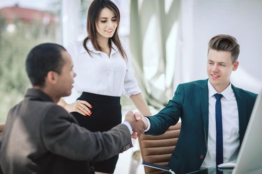 handshake of business partners sitting at a Desk .the concept of partnership