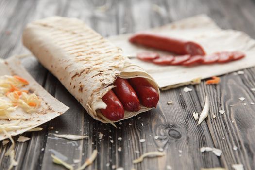 spicy sausages in pita bread on a wooden table.