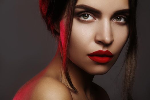 Beautiful model with fashion make-up. Sexy woman with glamour red lip makeup, strong eyebrows and bright eye shadows. Macro shot of celebrate visage, clean skin, lips with red lipstick.