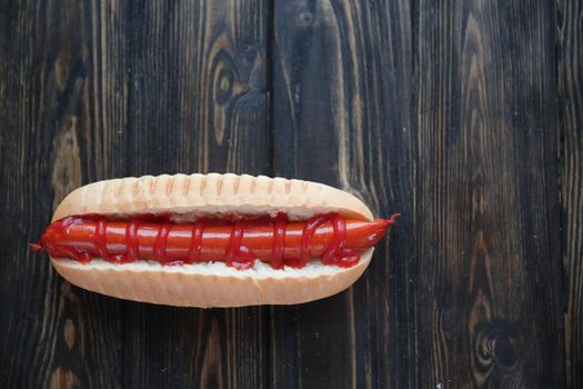 hot dog with smoked sausage on dark wooden background.photo with copy space.