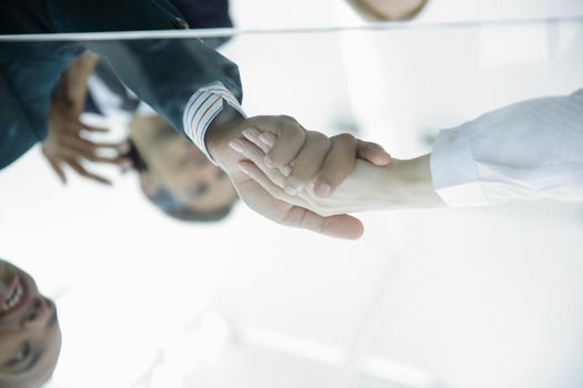 View from below. From behind the glass. Handshake of business partners