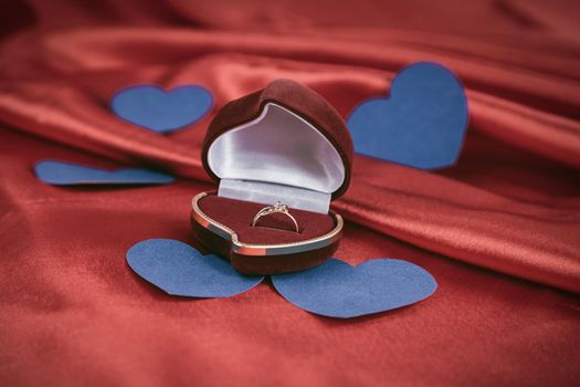 ring with a diamond on a red background . photo with copy space