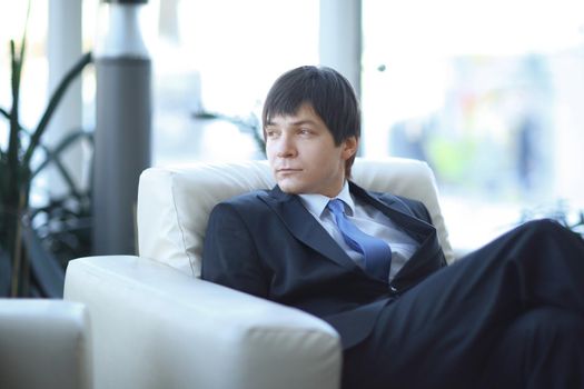 modern businessman sitting in a chair in the lobby of the modern office. photo with copy space