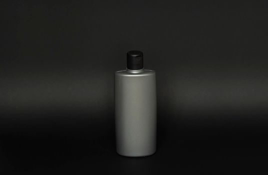 Gray bottle of shampoo, conditioner, hair rinse, mouthwash, on a black background