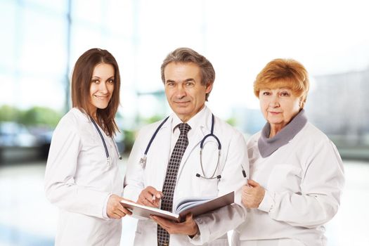 Cheerful doctors posing together, studying the important documents in bright office