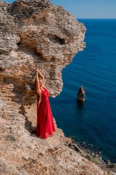 A woman in a red flying dress fluttering in the wind, against the backdrop of the sea