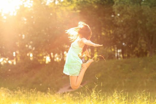 Happy girl in the rays of the setting sun