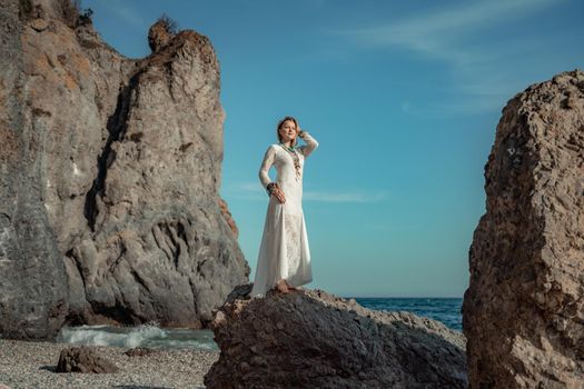 Middle aged woman looks good with blond hair, boho style in white long dress on the beach decorations on her neck and arms