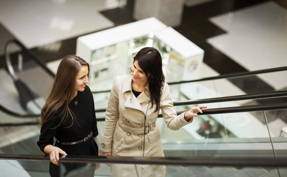 business people on escalator, two young businesswomen talking