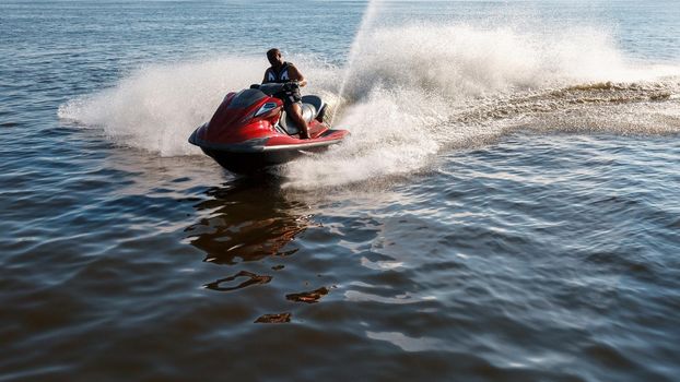 Man drives red jet ski on turquoise sea on a blue day