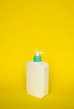 Shampoo or hair conditioner bottle with dispenser pump on yellow background