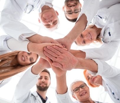 close up. group of different doctors putting their hands together . concept of unity.