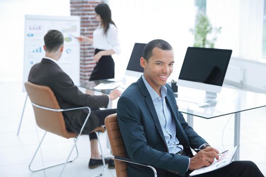 portrait of a young businessman on background of office.the concept of teamwork.