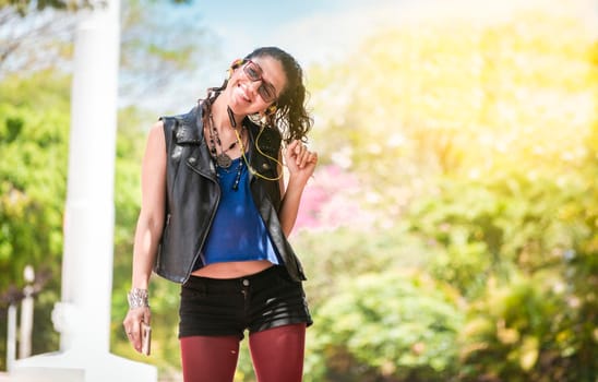 Latin girl listening to music outside, Urban girl enjoying music with headphones, happy woman listening to music outside, concept of girl listening to music