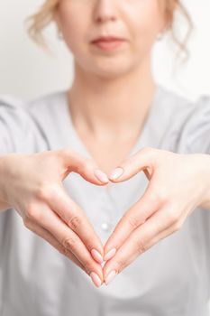 Close up of young caucasian woman making heart shape by hands. Romantic concept.
