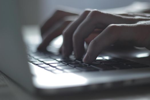 blurred image of male hand typing on laptop keyboard.close up.