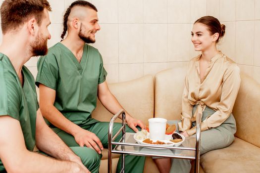 Young woman visiting two male massage therapists for a cup of tea.