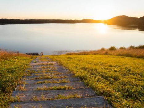 Beautiful sunset over Kenozero lake. Landscape with smooth water surface and wooden steps. Hiking in Karelia, Russia.