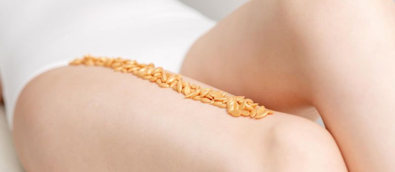 Wax beans or seed in row on legs of young woman lying on white background