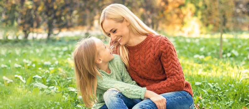 Happy smiling young caucasian mother and little daughter hugging each other outdoors. Happy family outdoor.