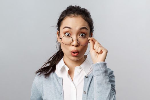 Advertisement, people and emotion concept. Close-up portrait of intrigued, excited asian female office employee, gossiping, realise something huge happened, hear big news, look surprised.