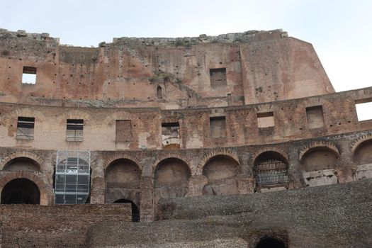 ROME, ITALY - February 05, 2022: Panoramic view around the Colosseum in city of Rome, Italy. Cold and gray sky in the background. Macro photography of the green parks with the old buildings.