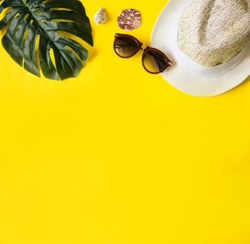 Beach accessories on the yellow background - sunglasses and striped hat. Summer is coming concept.Tropical leaves Monstera. Summer flat lay, top view. Space for text.