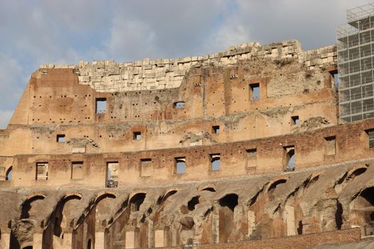 ROME, ITALY - February 05, 2022: Panoramic view around the Colosseum in city of Rome, Italy. Cold and gray sky in the background. Macro photography of the green parks with the old buildings.