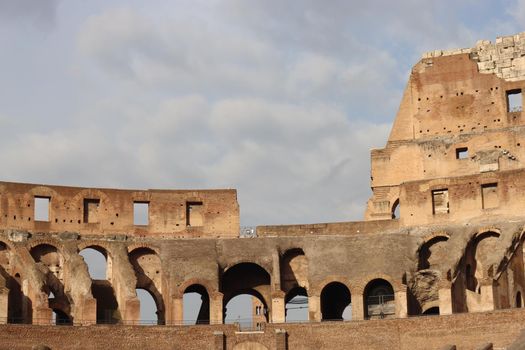 ROME, ITALY - February 05, 2022: Panoramic view around the Colosseum in city of Rome, Italy. Cold and gray sky in the background. Macro photography of the green parks with the old buildings.