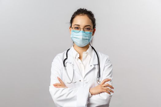 Covid19, coronavirus, healthcare and doctors concept. Portrait of professional confident young asian doctor in medical mask and white coat, stethoscope over neck, ready help patient, fight disease.