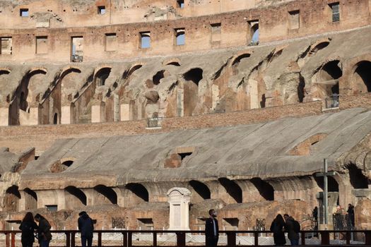 ROME, ITALY - February 05, 2022: Panoramic view around the Colosseum in city of Rome, Italy. Cold and gray sky in the background. Macro photography of the green parks with the old buildings.