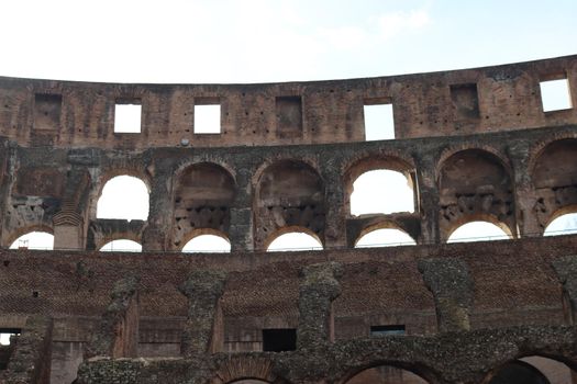 ROME, ITALY - February 05, 2022: Panoramic view around the Colosseum in city of Rome, Italy. Cold and gray sky in the background. Macro photography of the green parks with the old buildings.