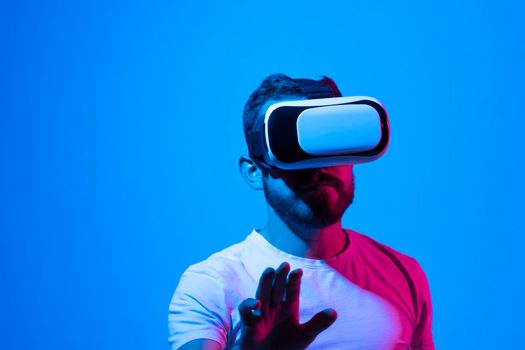 Amazed young bearded man, wearing high tech smart vr goggles, watching 360 degree video or playing a video game in metaverse