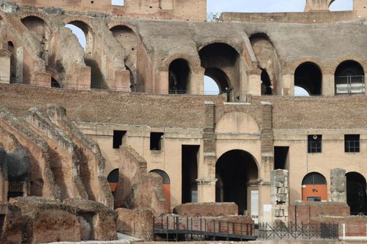 ROME, ITALY - February 05, 2022: Panoramic view around the Colosseum in city of Rome, Italy. Cold and gray sky in the background. Macro photography of the green parks with the old buildings.