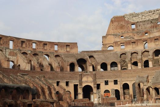 ROME, ITALY - February 05, 2022: Panoramic view around the Colosseum in city of Rome, Italy. Cold and gray sky in the background. Macro photography of the green parks with the old buildings.