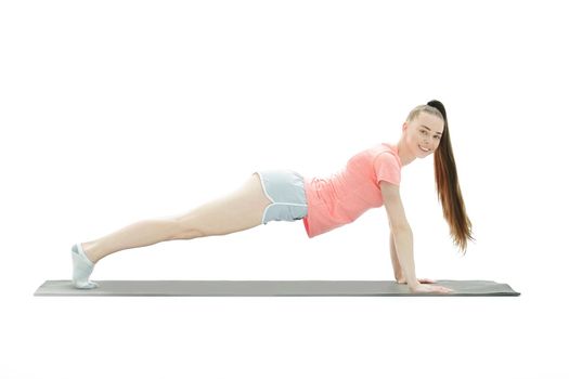 Young woman exercising - doing a plank in a studio.