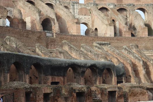 ROME, ITALY - February 05, 2022: Panoramic view around the Colosseum in city of Rome, Italy. Cold and gray sky in the background. Macro photography of the green parks with the old buildings.