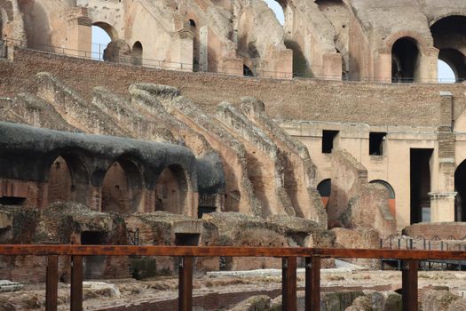 ROME, ITALY - February 05, 2022: Panoramic view around the Colosseum in city of Rome, Italy. Cold and gray sky in the background. Macro photography of the green parks with the old buildings.