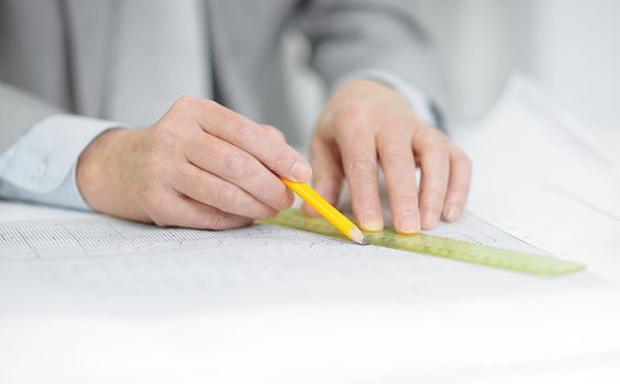 closeup .senior engineer makes a drawing sitting at his Desk