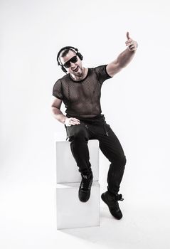 DJ - rapper in a stylish t-shirt with headphones and with hands up on white background . the photo has a empty space for your text