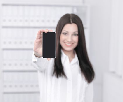 smiling female assistant showing a mobile phone standing in office.photo with copy space